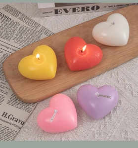 Detailed view of colorful woven heart scented candles on a wooden tray with a cozy home setting
