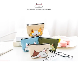 Close-up of four cute cartoon cat canvas coin purses stacked on magazines in a lifestyle setting