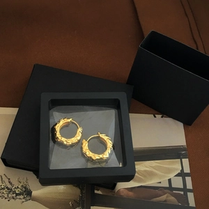 Lava-textured golden hoop earrings displayed in a black 3D floating frame jewelry box