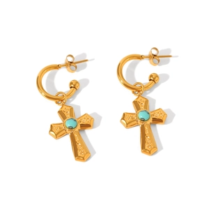 Detailed close-up of golden hoop earrings featuring a cross pendant and turquoise stone inlay
