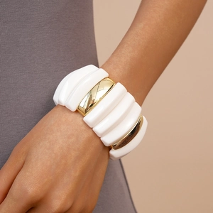 Detail of a white and gold acrylic elastic bracelet worn on a female wrist