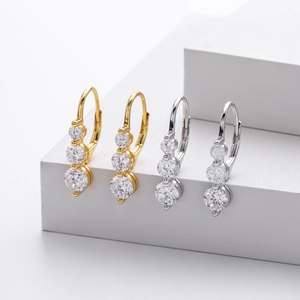 Détail de boucles d'oreilles en argent et or avec trois pierres en oxyde de zirconium