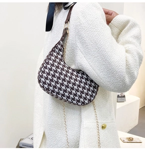 Detail view of houndstooth half-moon bag with brown leather trim and gold chain strap