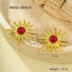 Macro detail of vintage gold sunflower earrings with red stones on a stone plate