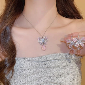 Detail of silver butterfly pendant necklace set with pink crystal drops on a model