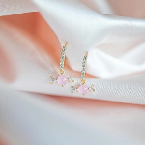 Candy-shaped earrings with pink stones and zircons on pink silk background