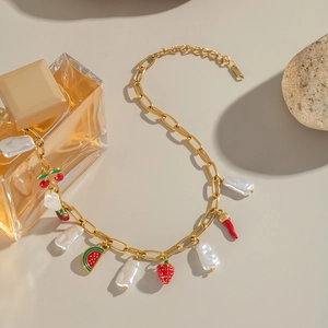 Bracelet doré avec perles et breloques fruits comme cerise et fraise sur fond beige élégant