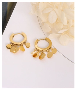 Detailed close-up of 18K gold-plated hoop earrings with five polished dangling metal sequins