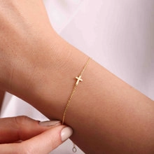 Vue macro d'un bracelet chaîne doré minimaliste avec un petit pendentif croix