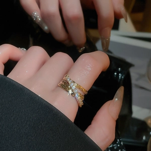 Macro shot of a triple-layer crisscross gold ring with zircon stones on a model hand