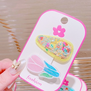 Detailed view of hair clips with colorful star sequins and pink tulip on display card