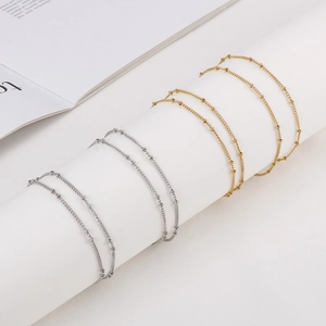 Gold and silver stainless steel ball chain necklaces displayed on white cylinder