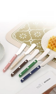 Set of five colorful stainless steel butter knives with ABS riveted handles on a table
