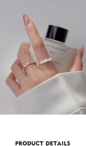 Detailed close-up of textured silver ring set with white pearls worn on a hand