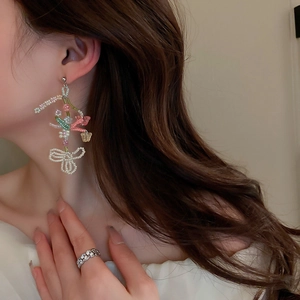 Close-up of handmade beaded floral earrings and sparkling zircon rings on model