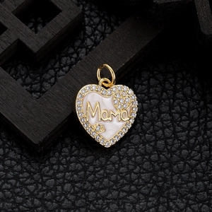 Macro shot of a gold heart pendant with Mama lettering and white enamel inlay