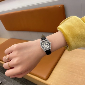 Elegant tonneau silver watch with diamond bezel and black leather strap worn on wrist