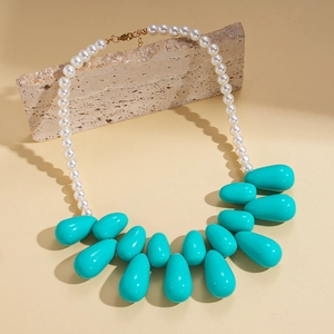 Detail of beaded necklace featuring white faux pearls and a large teal resin teardrop pendant