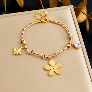 Detailed macro view of woven rope bracelet with gold star and purple crystal charms