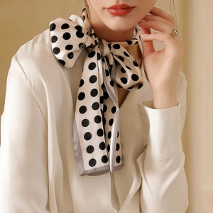 Close-up of elegant silk scarf with black polka dots tied gracefully on model neck