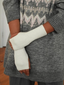 Close-up of white knitted fingerless gloves and arm warmers with detailed winter texture