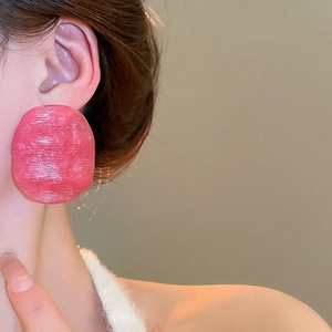 Close-up of oversized pink resin hoop earring with brushed texture on female model