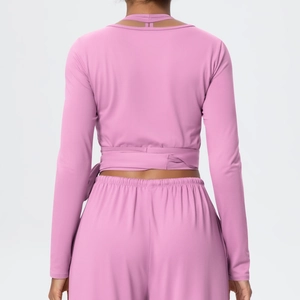 Detailed back view of pink long sleeve yoga top with crisscross wrap tie design