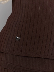 Gros plan sur le tricot côtelé marron foncé avec un petit pendentif cœur en métal argenté