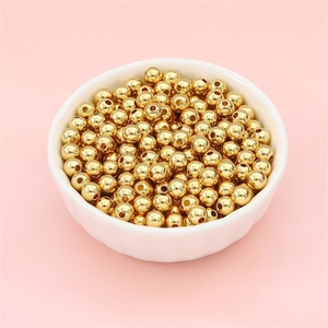 Polished 14k gold-filled round spacer beads for DIY jewelry making in a white bowl