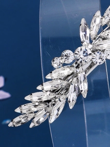 Detail of silver feather hair clip with sparkling rhinestones on dark blue background