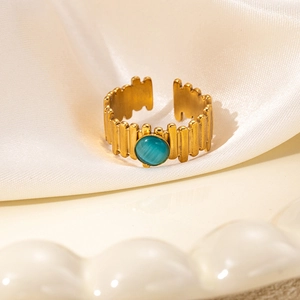 Detail of vintage gold ring with teal gemstone on soft white silk backdrop