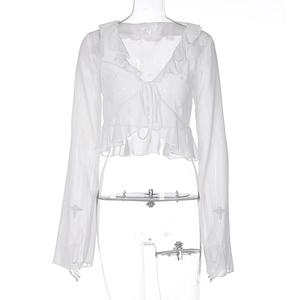 Detail of white sheer long sleeve top featuring ruffle trim and front tie closure