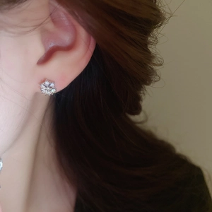 Close-up of elegant silver snowflake stud earrings with sparkling zircon on a model's ear
