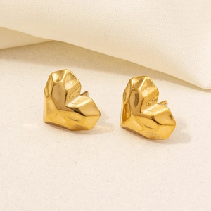 Polished gold heart-shaped geometric stud earrings in stainless steel on beige fabric