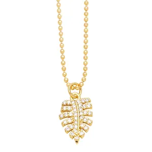 Minimalist golden beaded necklace with a crystal monstera leaf pendant on white backdrop