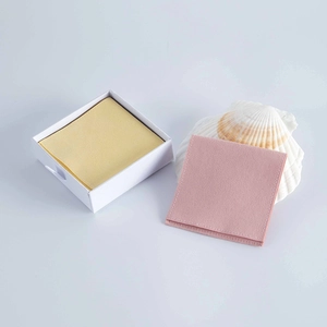 Macro shot of pink velvet jewelry pouch and yellow cleaning cloth by white shell