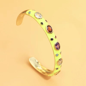 Macro detail of gold C-shaped open bangle with neon enamel and colorful zircon inlay