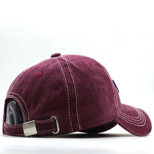 Detail of burgundy washed cotton baseball cap with white stitching and metal buckle