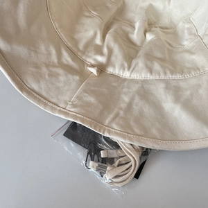 Detail of beige cotton bucket hat stitching and adjustable windproof rope accessory