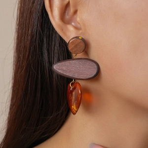 Macro detail of vintage resin teardrop and wood circle earrings worn by a model