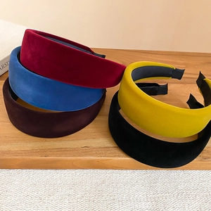 Detailed view of wide velvet headbands in assorted colors on a wooden surface