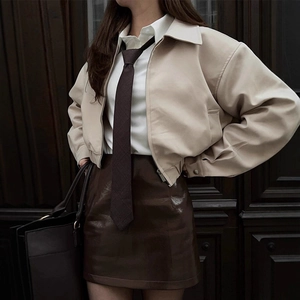 Detail of beige lapel zip-up jacket with brown PU leather skirt and tote bag
