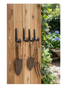 Close-up of four black cast iron vintage wall hooks mounted on rustic wooden panels
