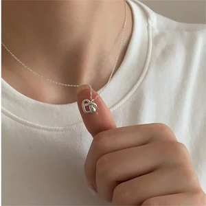 Close-up of minimalist S925 sterling silver twisted heart pendant necklace on finger