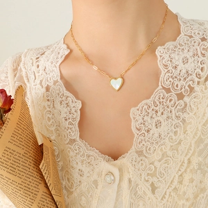 18K gold plated titanium necklace with heart shell pendant on a vintage paper backdrop