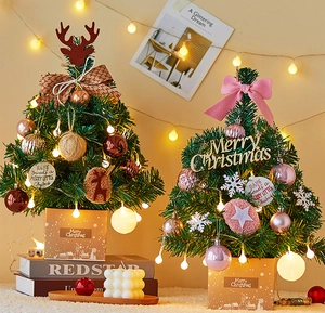 Close-up of mini Christmas tree with LED lights, festive ornaments and a gift box base