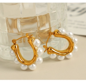 Close-up of elegant U-shaped pearl earrings with gold-toned setting and white pearls
