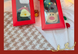 Festive Christmas gift box with reindeer and tree ornaments on patterned fabric