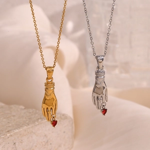 Detail of vintage hand-shaped pendants in gold and silver finish with red heart charms