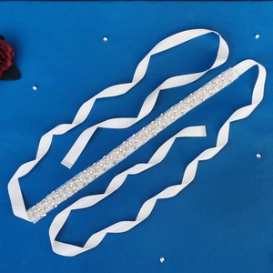 Detailed view of bridal crystal belt with pearls and white satin ribbon on blue background